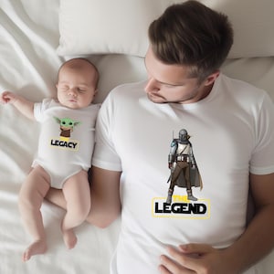 a man is holding a baby wearing a star wars shirt