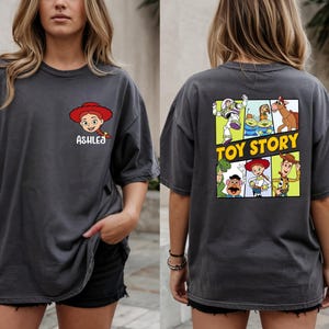 A woman wearing a gray t-shirt with a graphic of characters from the Toy Story movie on the back.