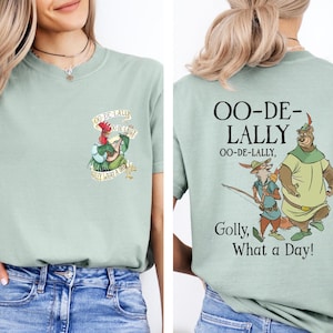 Op de afbeelding: Lichtgroen T-shirt met cartoonafbeeldingen uit een klassieke animatiefilm. De voorkant heeft een hanenpersonage met tekst. De achterkant heeft de woorden "OO-DE-LALLY" en een cartoonvos en berenpersonage met tekst.