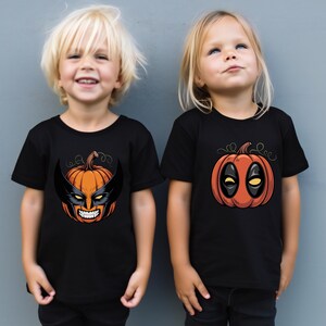 Two young children wearing black t-shirts with Halloween-themed designs, including a pumpkin and a mask.