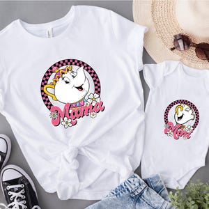 May include: White t-shirt and onesie set featuring a cartoon teapot design with the word "Mama" and "Mom" in pink script. The design is surrounded by a pink and black checkered circle and white flowers. Black sneakers are visible.