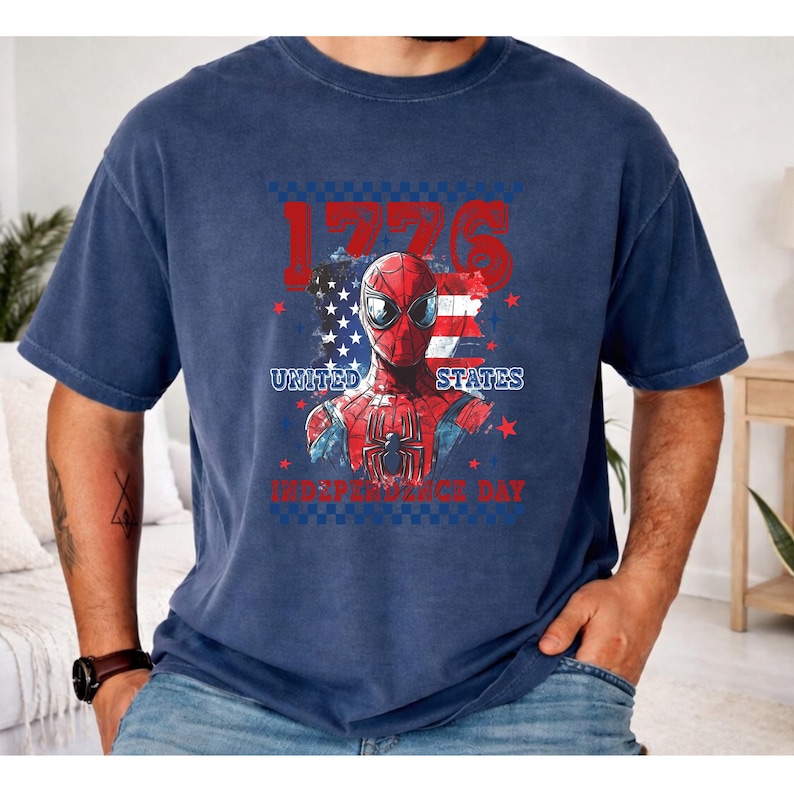 May include: Navy blue t-shirt featuring a graphic of Spider-Man with the American flag and the text "1776 United States Independence Day". The design incorporates red, white, and blue colors, celebrating the holiday.