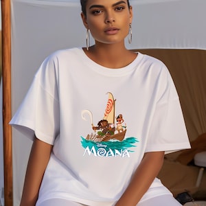 May include: White t-shirt with a graphic of Moana and Maui sailing on a boat with the text "Disney Moana" on the front.