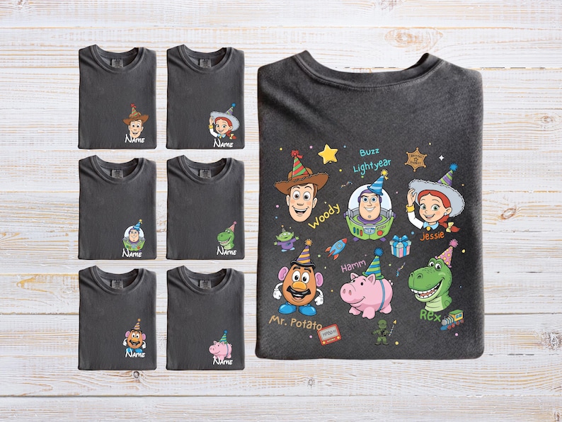 Puede incluir: Camisetas gris oscuro con varios personajes de Toy Story, incluyendo a Woody, Buzz Lightyear y Jessie. Cada camiseta tiene un gr&aacute;fico de personaje y la palabra "Name" debajo. La camiseta m&aacute;s grande muestra varios personajes.