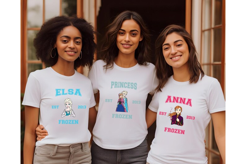 May include: Three white t-shirts with Frozen characters and text. The first shirt says "Elsa Est 2013 Frozen" and features Elsa. The second shirt says "Princess Est 2013 Frozen" and features Elsa and Anna. The third shirt says "Anna Est 2013 Frozen" and features Anna.