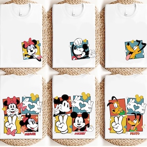 May include: White t-shirts featuring colorful cartoon character designs. The designs include Minnie Mouse, Mickey Mouse, and Pluto. Each character is set in a square with a unique background. The shirts are displayed on a woven surface.
