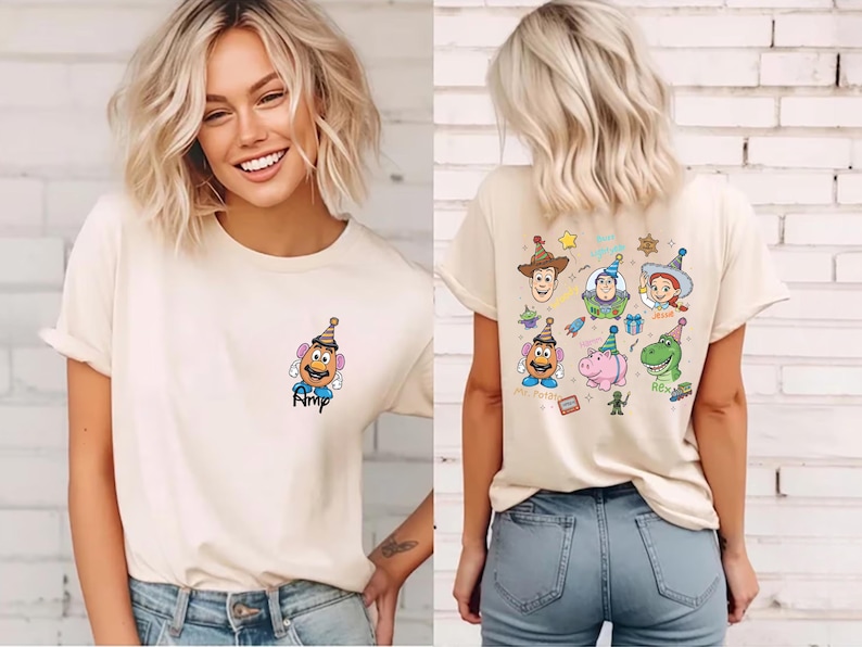 Puede incluir: Camiseta color crema con una imagen de dibujos animados de Mr. Potato Head en la parte delantera, con el nombre "Amp" debajo. La parte posterior de la camiseta muestra varios personajes de Toy Story, incluyendo Woody, Buzz Lightyear y Rex.