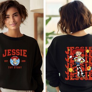 May include: Black sweatshirt featuring the name "JESSIE" in red collegiate lettering, with "EST. 1999 TOY STORY" below. The back displays a retro design of the character Jessie from Toy Story, with her name repeated.