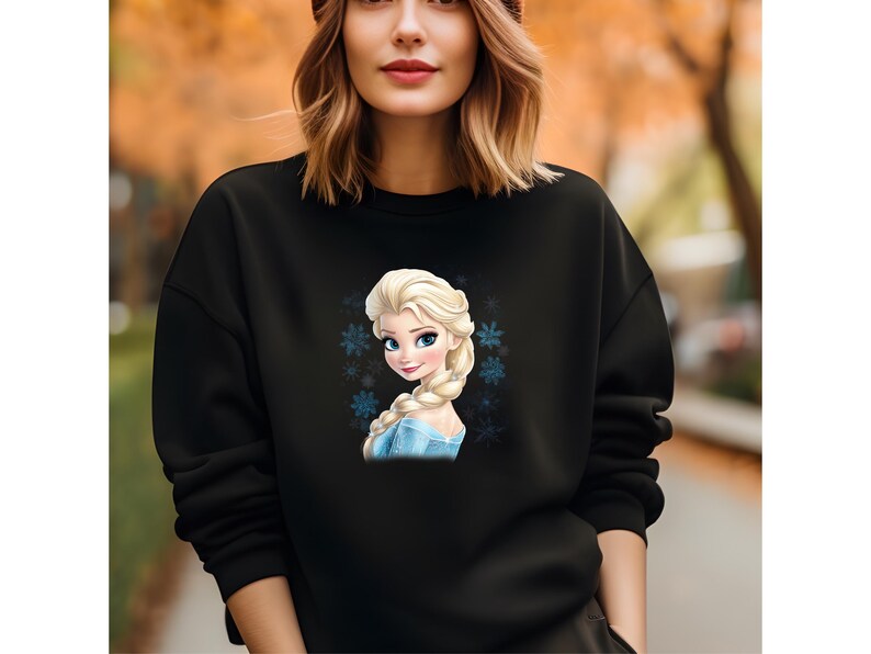 May include: Black sweatshirt with a graphic print of a cartoon character with blonde hair and a blue dress. The character is surrounded by snowflakes.