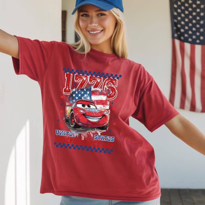 A smiling woman wearing a red t-shirt with a graphic of a red car and an American flag design.