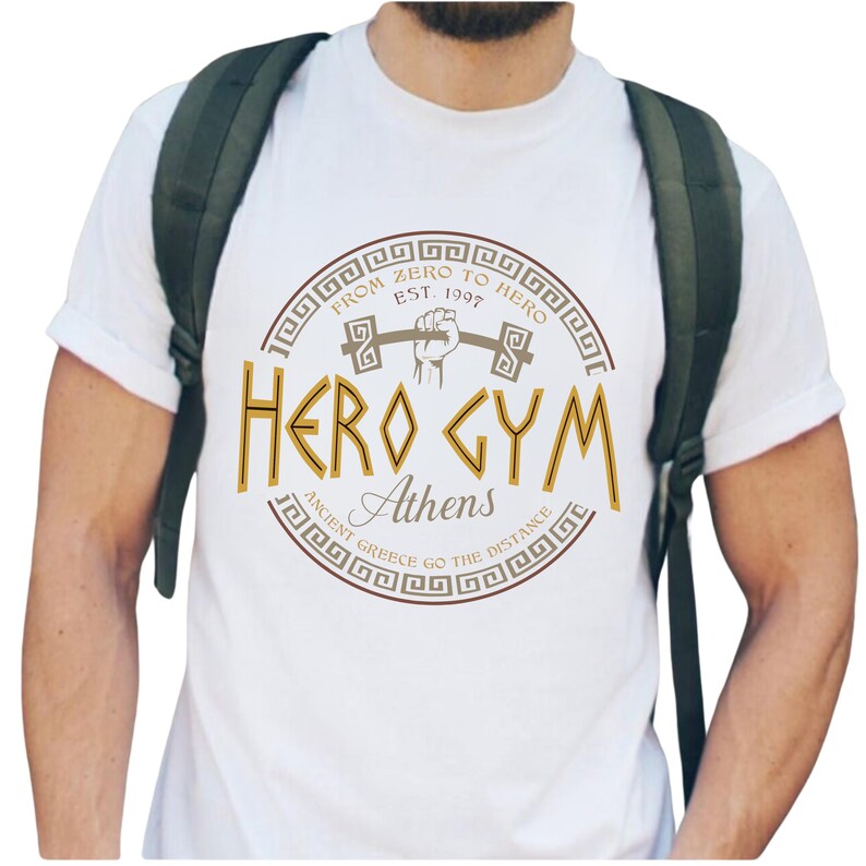 A white t-shirt with a graphic design featuring a fist and the text "HERO GYM Athens" printed on it.