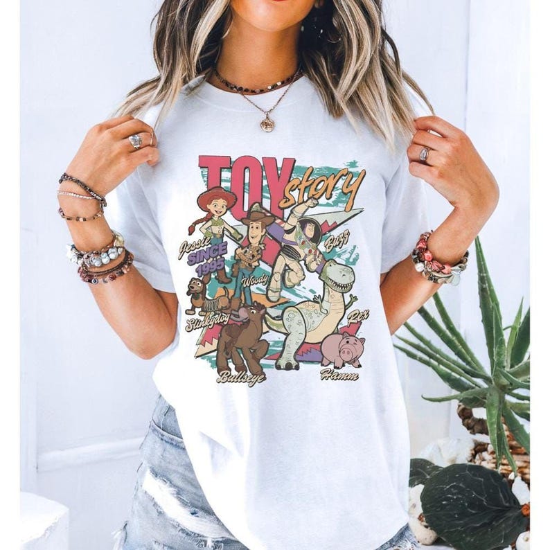 A woman wearing a white t-shirt with a colorful graphic of characters from the Toy Story movie.