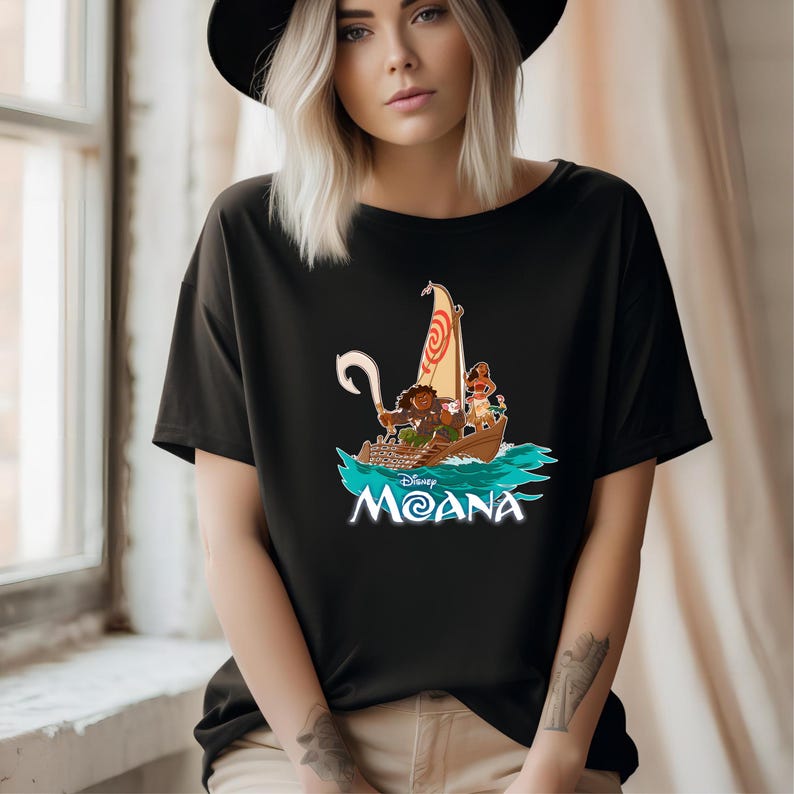 May include: Black t-shirt with a graphic of Moana and Maui sailing on a boat in the ocean. The text "Disney Moana" is printed below the image.
