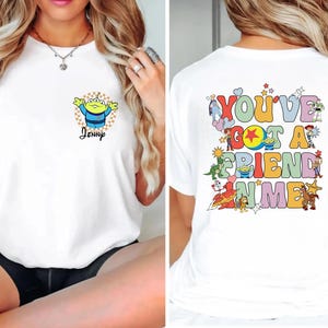May include: White t-shirt featuring a cartoon alien with the name "Jenny" on the front. The back of the shirt displays the phrase "You've Got A Friend In Me" with various cartoon characters.