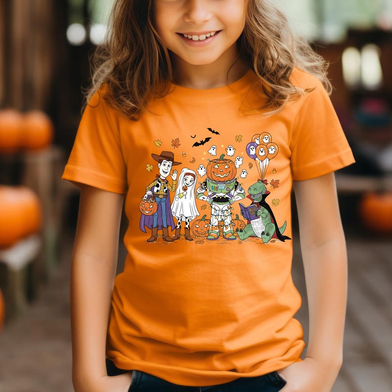 A young girl wearing an orange t-shirt with a Halloween-themed graphic of characters from Toy Story.