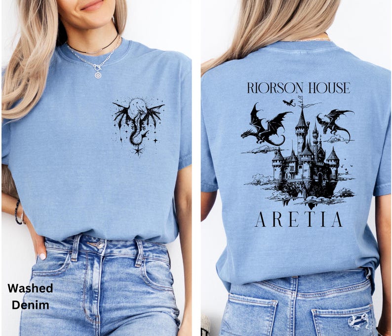 May include: Light blue t-shirt with a black dragon and moon graphic on the front and a castle with dragons on the back. The text "RIORSON HOUSE ARETIA" is printed on the back. The shirt is made of a soft material.