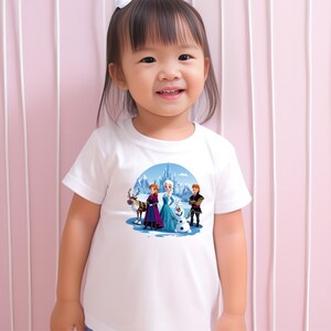 May include: A white t-shirt with a colorful graphic of characters from the movie Frozen. The graphic features Elsa, Anna, Kristoff, and Olaf standing in front of a castle.