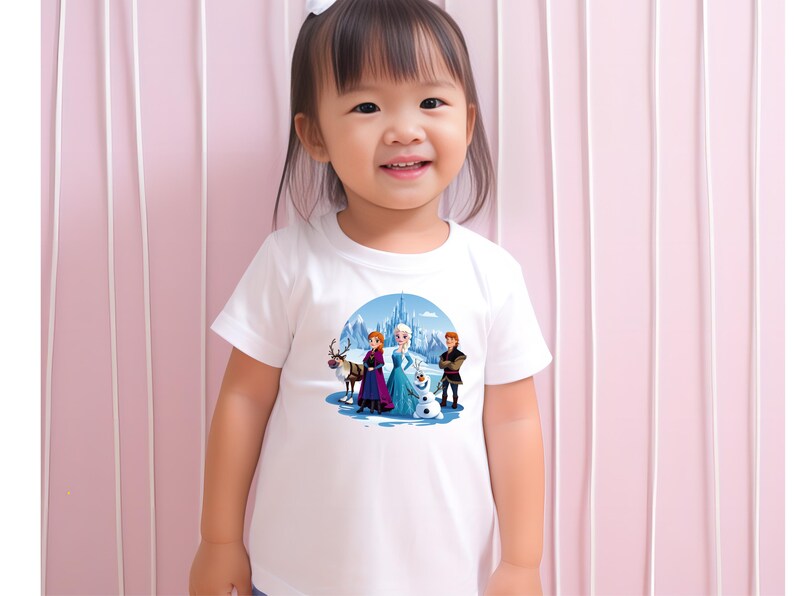 May include: A white t-shirt with a colorful graphic of characters from the movie Frozen. The graphic features Elsa, Anna, Kristoff, and Olaf standing in front of a castle.