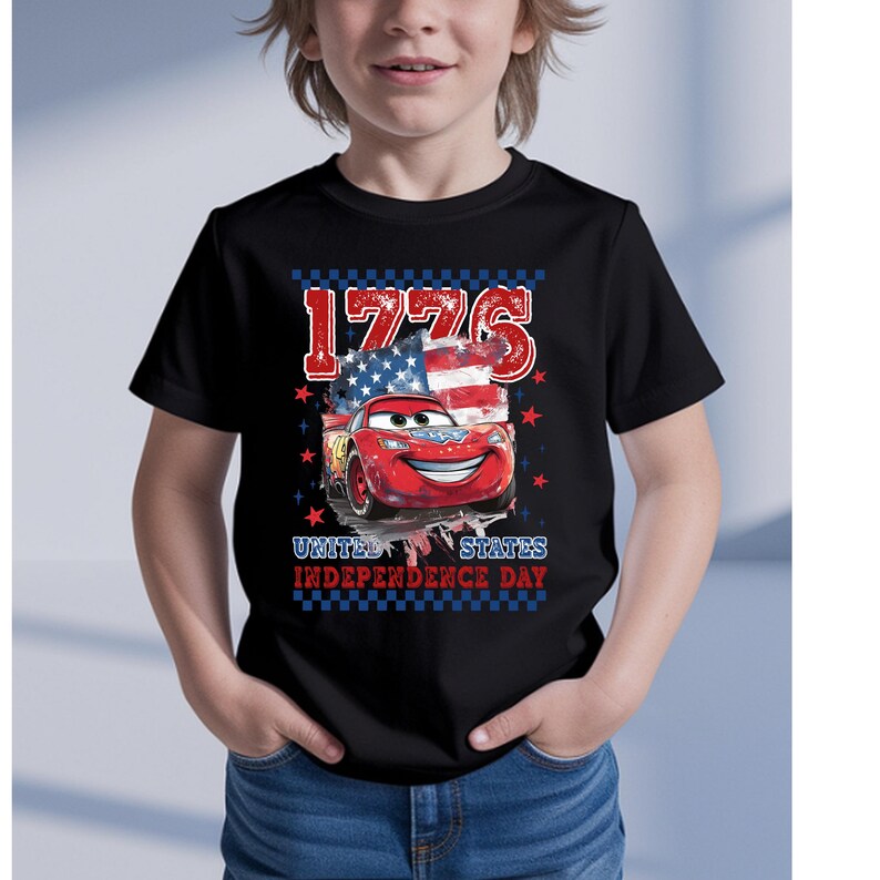 A young boy wearing a black t-shirt with a graphic design featuring a red car and an American flag, along with the text "1776" and "UNITED STATES INDEPENDENCE DAY".
