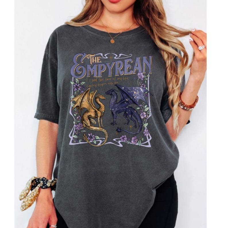 Pode incluir: Camiseta cinza escuro com um design de dois drag&otilde;es, um dourado e outro roxo, voltados um para o outro. O texto "The Empyrean" est&aacute; acima dos drag&otilde;es, com texto adicional abaixo. Acentos florais emolduram o design.