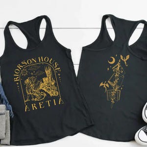 Może przedstawiać: Czarny tank top ze złotą ilustracją gryfa, zamku i napisem "RIORSON HOUSE ARETIA". Tył tank topu zdobi złoty wz&oacute;r książek, smok&oacute;w i p&oacute;łksiężyca.