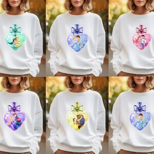 Puede incluir: Seis sudaderas blancas con un dise&ntilde;o en forma de coraz&oacute;n que presenta una pareja de una pel&iacute;cula de Disney. Los corazones est&aacute;n llenos de un dise&ntilde;o similar a la acuarela y tienen un lazo azul en la parte superior.