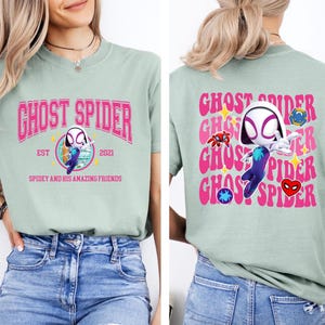 a woman wearing a green t-shirt with a graphic design of a character resembling Spider-Man.