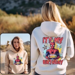 A woman wearing a white hoodie with a Spider-Man design and text on the back.