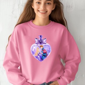Puede incluir: Sudadera rosa con un dise&ntilde;o de botella en forma de coraz&oacute;n morado que presenta un pr&iacute;ncipe y una princesa en su interior. La botella tiene un lazo morado en la parte superior.