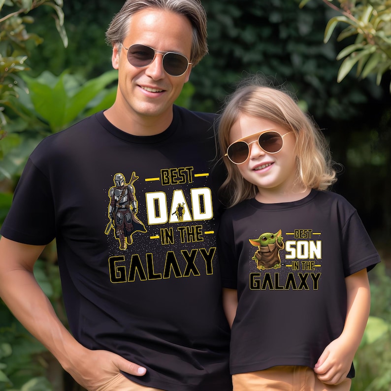 Pu&ograve; includere: T-shirt nere con grafica abbinata. Una maglietta dice "Best Dad in the Galaxy" con una grafica di Mandaloriano. L'altra dice "Best Son in the Galaxy" con una grafica di Grogu.