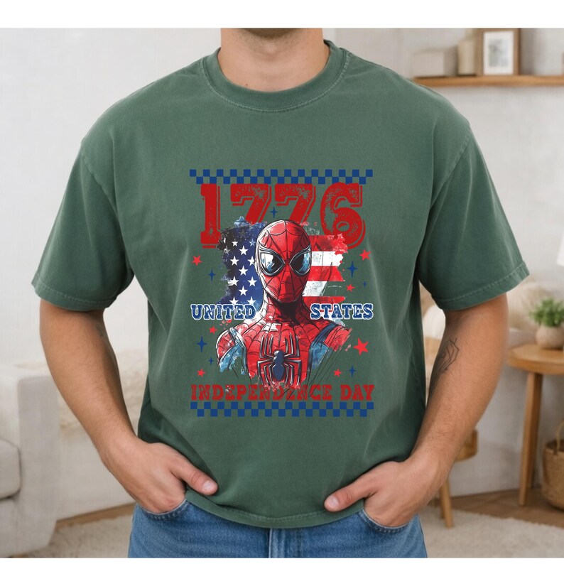 May include: Green t-shirt featuring a graphic of Spider-Man with the American flag and the text "1776 United States Independence Day". The design is in red, white, and blue.