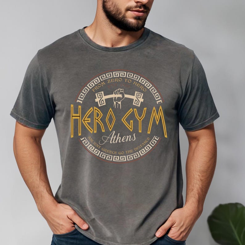 A man wearing a gray t-shirt with a graphic design featuring text and a symbol.