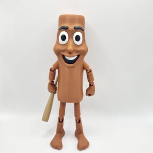 Puede incluir: Una figura de juguete articulada de color marr&oacute;n con una cara sonriente, que lleva un atuendo marr&oacute;n y sostiene un bate de b&eacute;isbol de madera.