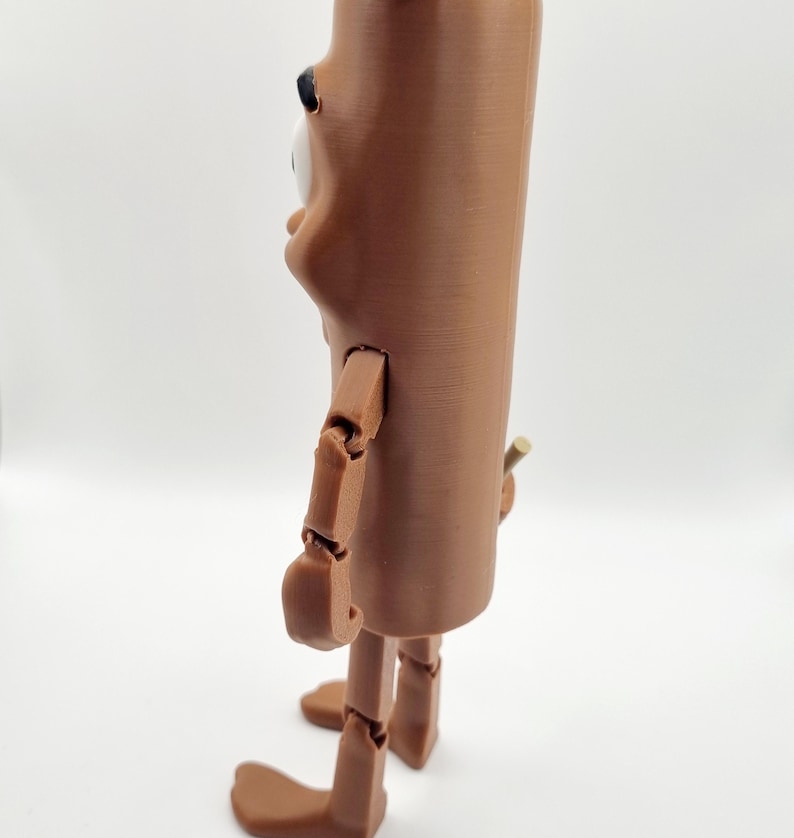 Puede incluir: Una figura articulada marr&oacute;n con un cuerpo largo y cil&iacute;ndrico y una cabeza grande y redonda. La figura tiene un solo ojo grande y una nariz peque&ntilde;a y puntiaguda. Los brazos y las piernas de la figura est&aacute;n articulados en las articulaciones, lo que permite una variedad de poses.