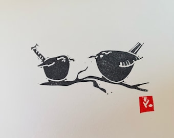 May include: Black and white linocut print of two birds perched on a branch. The print is signed with a red stamp in the bottom right corner.
