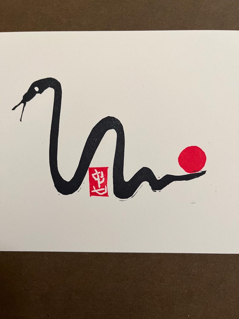 Peut inclure: Dessin &agrave; l'encre noire et blanche d'un serpent avec un cercle rouge et un tampon rouge avec le caract&egrave;re chinois "生" sur fond blanc.