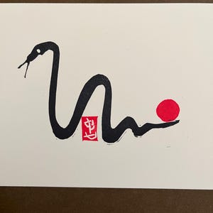 Peut inclure: Dessin &agrave; l'encre noire et blanche d'un serpent avec un cercle rouge et un tampon rouge avec le caract&egrave;re chinois "生" (prononc&eacute; shēng, signifiant "vie") sur un fond blanc.