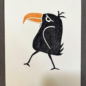 May include: A black and orange cartoon bird with an angry expression. The bird has a long beak and is standing on two legs.