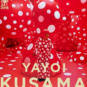 Peut inclure: Affiche rouge avec des sculptures à pois blancs et une personne vêtue d'une tenue à pois. Le texte "LOUISIANA" et "YAYOI KUSAMA" est écrit en crème. Une œuvre d'art visuellement frappante.