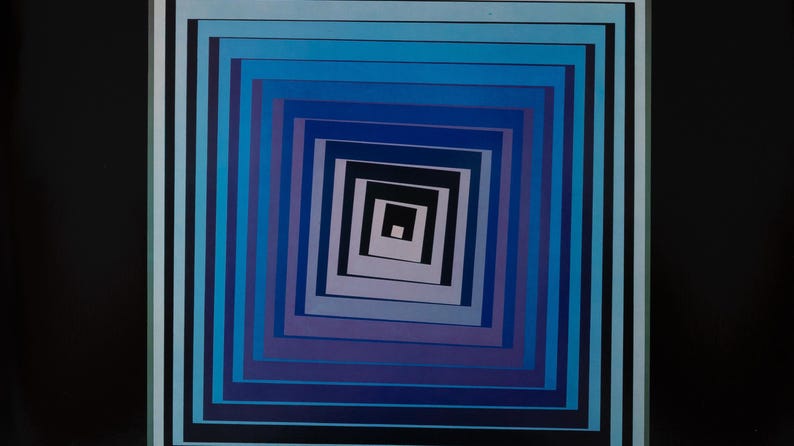 May include: Abstract geometric art print featuring concentric squares in shades of blue, purple, and black. The artwork creates a visual tunnel effect, with a dark background. The piece is framed with a white and black border.