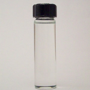 May include: A clear glass bottle with a black screw-on cap. The bottle is filled with a clear liquid.