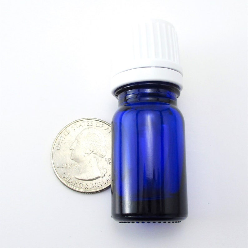 May include: A small, cobalt blue glass bottle with a white plastic cap. The bottle is about the size of a US quarter.