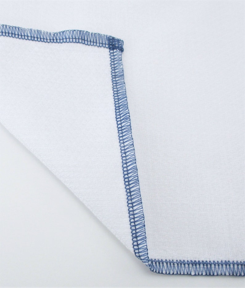 May include: A white fabric square with a blue stitched border.