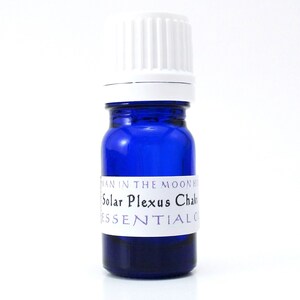 May include: A small blue glass bottle with a white cap. The bottle is labeled "Solar Plexus Chakra Essential Oil" and "Woman in the Moon Herbs".