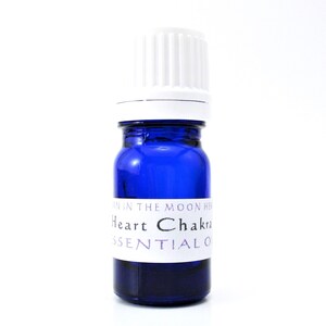 May include: A blue glass bottle with a white label that reads "Heart Chakra Essential Oil". The bottle has a white cap.