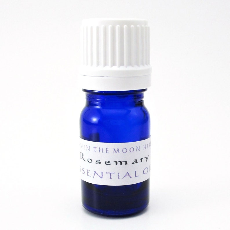 May include: A small blue glass bottle with a white cap. The bottle is labeled "Rosemary Essential Oil" and "Moon Herbs".