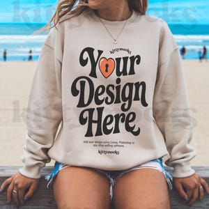 May include: A beige sweatshirt with a retro-style graphic that says "Your Design Here" with a heart and keyhole design. The text "kittymocks" appears above and below the graphic.