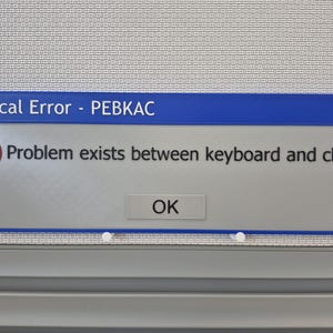 May include: A blue-framed window with the text "Critical Error - PEBKAC" at the top. The window displays an error message: "Problem exists between keyboard and chair." An "OK" button is visible.
