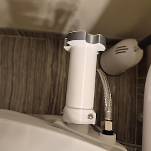 May include: White toilet tank with a white plastic pipe and a gray plastic connector. The pipe is connected to a silver hose.