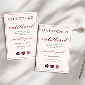 May include: Two white cards with red borders and black text that reads "Unhitched and Unbothered" in a cursive font. The cards also include the text "Samantha prutt" and "October 18th @ 6PM" with the address "123 Anywhere Street, Any city". The cards have three small heart-shaped sweets on them, one black, one red, and one pink.